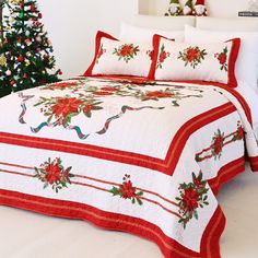 a christmas themed bed spread with poinsettis and holly on it, next to a christmas tree