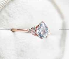 an engagement ring with a blue topazte surrounded by three white diamonds in rose gold