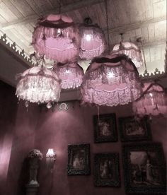 pink chandeliers hanging from the ceiling in a room with pictures on the wall