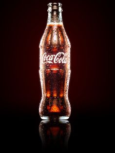 an illuminated coca cola bottle on a black background