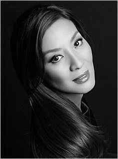 a woman with long dark hair posing for a photo in front of a black background