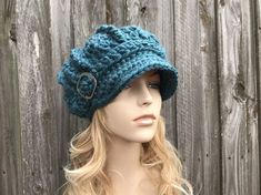 a mannequin head wearing a blue crochet hat on top of a wooden fence