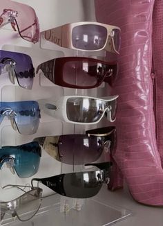 several pairs of sunglasses on display in front of a pink wall with an alligator skin pillow