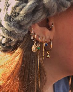 a close up of a person's ear wearing different earrings and piercings on their ears