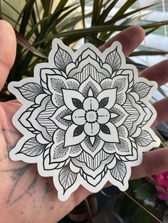 a hand holding a black and white sticker with an intricate flower design on it