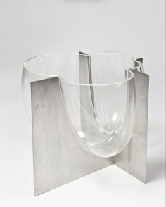 a clear glass vase sitting on top of a metal stand in front of a white background