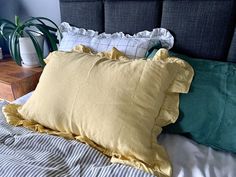 a bed with two pillows on top of it next to a potted houseplant