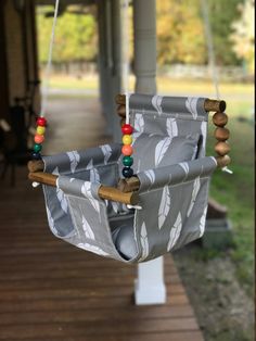 a gray and white swing chair with beads on the strings hanging from it's sides