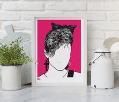 a pink poster with a woman's face on the wall next to a potted plant