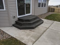 three steps leading up to the front door of a house with gravel on the ground