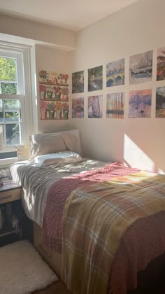 a bed sitting in a bedroom next to a window with pictures on the wall above it