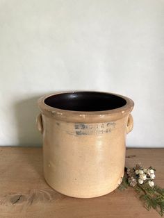 a small pot sitting on top of a wooden table next to a planter with flowers growing out of it