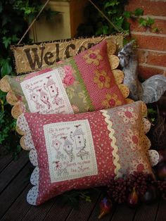 four pillows sitting on top of a wooden floor next to a brick wall and green plants