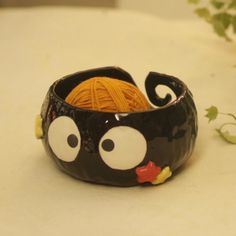 a black and white bowl with yarn in the shape of a cat's head