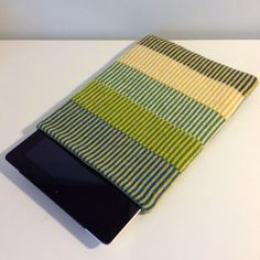 the tablet is covered with a multi - colored striped cloth, and sits on top of a white table