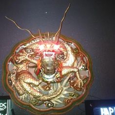 a clock with two dragon heads on it's face and lights in the background