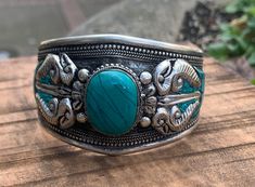 Vajra or Dorje Cuff bracelet. This is a beautiful Tibetan inspire Tribal Cuff with Vajra and Turquoise in the middle. Turquoise stone in the middle is carefully nested in the metal strip and also has inlaid turquoise around the cuff with intricate hand work. Made with a beautiful old time vintage appeal to it. Casual and cool piece to match with any outfit. Completely adjustable to any adult wrist size and is very comfortable to wear. Perfect for Male or Female. Size: 2.75" X 1.60" Bohemian Turquoise Bangle For Festivals, Adjustable Turquoise Bangle For Festivals, Turquoise Bangle Bracelet For Festival, Bohemian Turquoise Nickel-free Cuff Bracelet, Handmade Turquoise Spiritual Bangle, Handmade Spiritual Turquoise Bangle, Adjustable Turquoise Cuff Bangle, Adjustable Turquoise Cuff Bracelet, Adjustable Turquoise Cuff Bracelet For Festivals