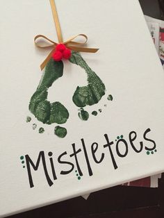 a handprinted christmas card with the word mistle toes on it and a ribbon