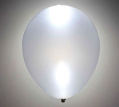 a large white balloon floating in the air with a light on it's side