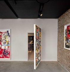 three paintings are on the wall in an empty room with exposed ceilings and exposed brick walls