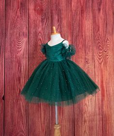 Little Darln Boutique  Our enchanting Knee Length flower girl dresses are sure to turn heads! This beautiful elegant dress is handmade, the bodice consists of Hunter Green satin with a layer of pearl tulle, followed by spaghetti straps and of the shoulder tulle sleeves. The back of the dress has a zipper for closure. The skirt consists of 4 Hunter Green layers of tulle with the top layer consisting of pearl beads. The fifth layer is made of lining with crinoline for fullness.  This dress is perfect for any occasion!  Dress Is Pictured with a petticoat NOT INCLUDED https://www.etsy.com/listing/1316417982/white-knee-length-petticoat-wedding?click_key=41cb8b0ae4587efa582b0a433f3f5e0cde12aec0%3A1316417982&click_sum=af1df37b&ref=shop_home_active_1 Visit our store, more items to come!  https://w Elegant Christmas Princess Dress In Tulle, Elegant Tulle Holiday Dress For Festive Occasions, Elegant Christmas Tulle Princess Dress, Elegant Tulle Ball Gown For Christmas, Elegant Christmas Tulle Ball Gown, Elegant Christmas Tutu Dress In Tulle, Fitted Tutu Dress For Christmas Fancy Dress, Elegant Christmas Tulle Tutu Dress, Fitted Christmas Tutu Dress For Fancy Dress