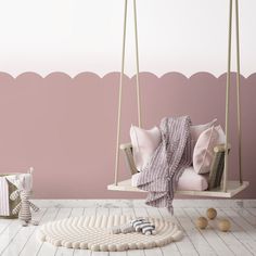 a pink and white room with a swing chair, pillows and other items on the floor