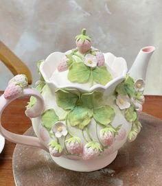 a tea pot with flowers and leaves painted on it