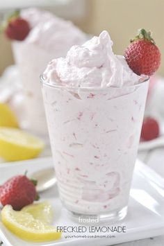 there is a dessert with whipped cream and strawberries in the glass on the table