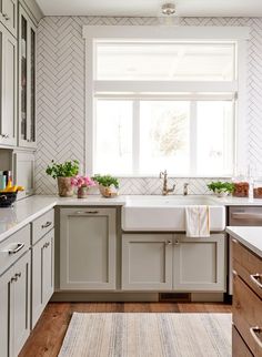 a kitchen with white cabinets and blue counter tops is pictured in this image, there are flowers on the window sill