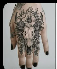 a woman's hand with flowers and a skull on the middle of her palm