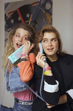 two young women are talking on the telephone