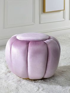 a purple stool sitting on top of a white rug next to a painting and framed pictures