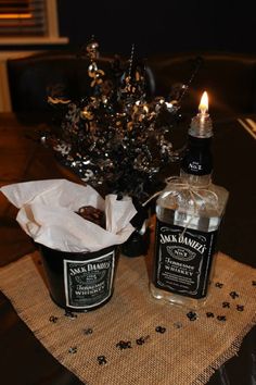 two bottles of jack daniels are sitting on a table next to a candle and some napkins