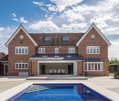 a large brick house with a swimming pool in the foreground and an attached garage