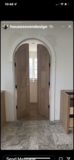 an open door in the middle of a room with marble flooring and white walls