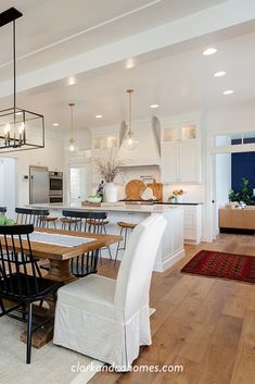 a dining room table and chairs in front of an open kitchen area with white cabinets