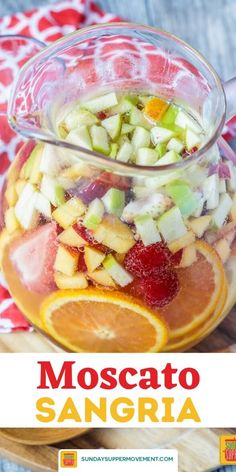 a glass pitcher filled with fruit salad on top of a wooden cutting board