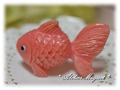 a pink fish figurine sitting on top of a white doily covered table