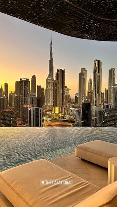 an outdoor lounge area with cityscape in the background and water reflecting off to the side