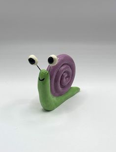 a purple and green snail figurine with two eyes on it's head