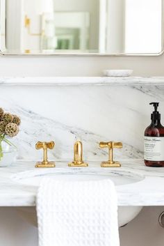 a bathroom with marble counter top and gold faucets