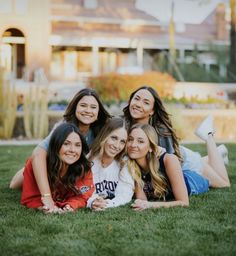 a group of young women laying on top of a lush green field next to each other