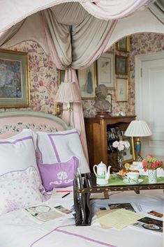 a bed room with a neatly made bed next to a table and lamps on it