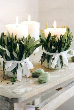 candles wrapped with greenes are sitting on a table