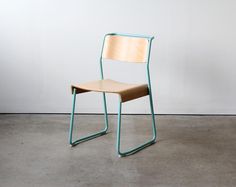 a wooden chair sitting on top of a cement floor next to a whiteboard wall