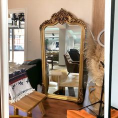 a large gold mirror sitting on top of a wooden floor next to a living room