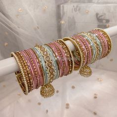 Large stack of luxurious antique Gold bangles with Pale mint and an Ombre of pink shades finished with Champagne Crystal Jhumka drop bangles and pearl ends. This will make the perfect stack for any Bride or those wanting to make a statement. Pair this with our Aafiya Bridal Set. Sold as a set for both arms only. Ready to Ship! Bohemian Pink Festive Bangle, Pink Beaded Bangle Bracelets For Wedding, Pink Stackable Jewelry For Festive Occasions, Festive Pink Stackable Bracelets, Festive Pink Stackable Jewelry, Pink Bollywood Bracelets For Celebration, Pink Meenakari Bangle For Wedding, Pink Meenakari Wedding Bracelets, Pink Bollywood Celebration Bracelets