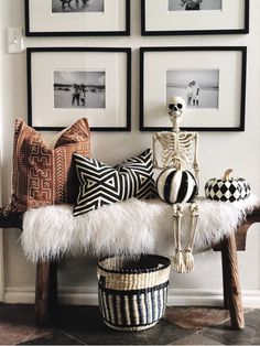 a skeleton sitting on a bench in front of some framed pictures and other decorative items