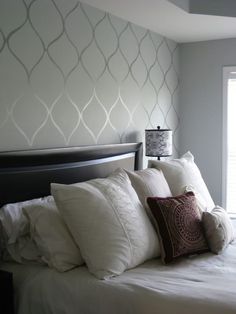 a bed with white sheets and pillows next to a window