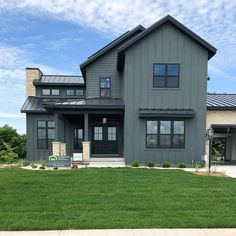 a large gray house sitting on top of a lush green field